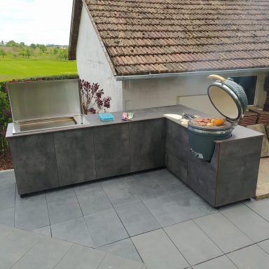 Moderne Außenküche mit Grill und Arbeitsfläche Moderne Außenküche mit Grill und Arbeitsfläche, umgeben von Rasen und Bäumen.